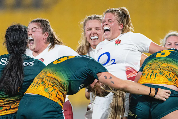 Three England rugby players in white shirts celebrate.