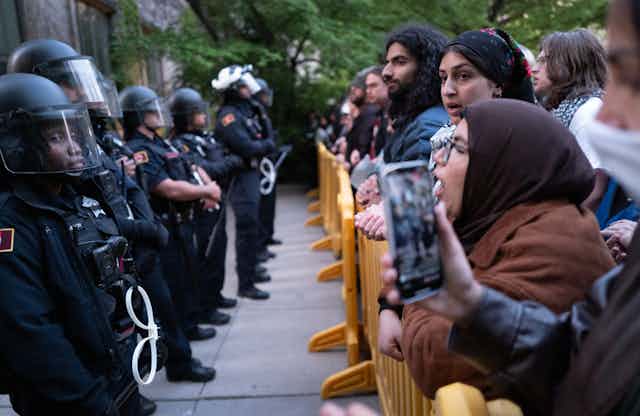 Protesters confront police in riot gear.