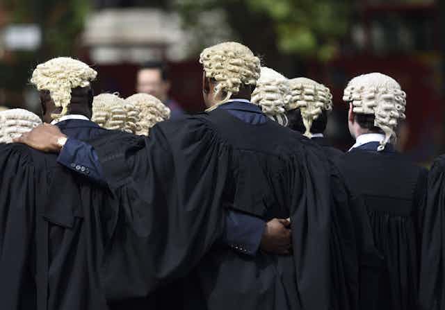 A group of bewigged barristers seen from behind.
