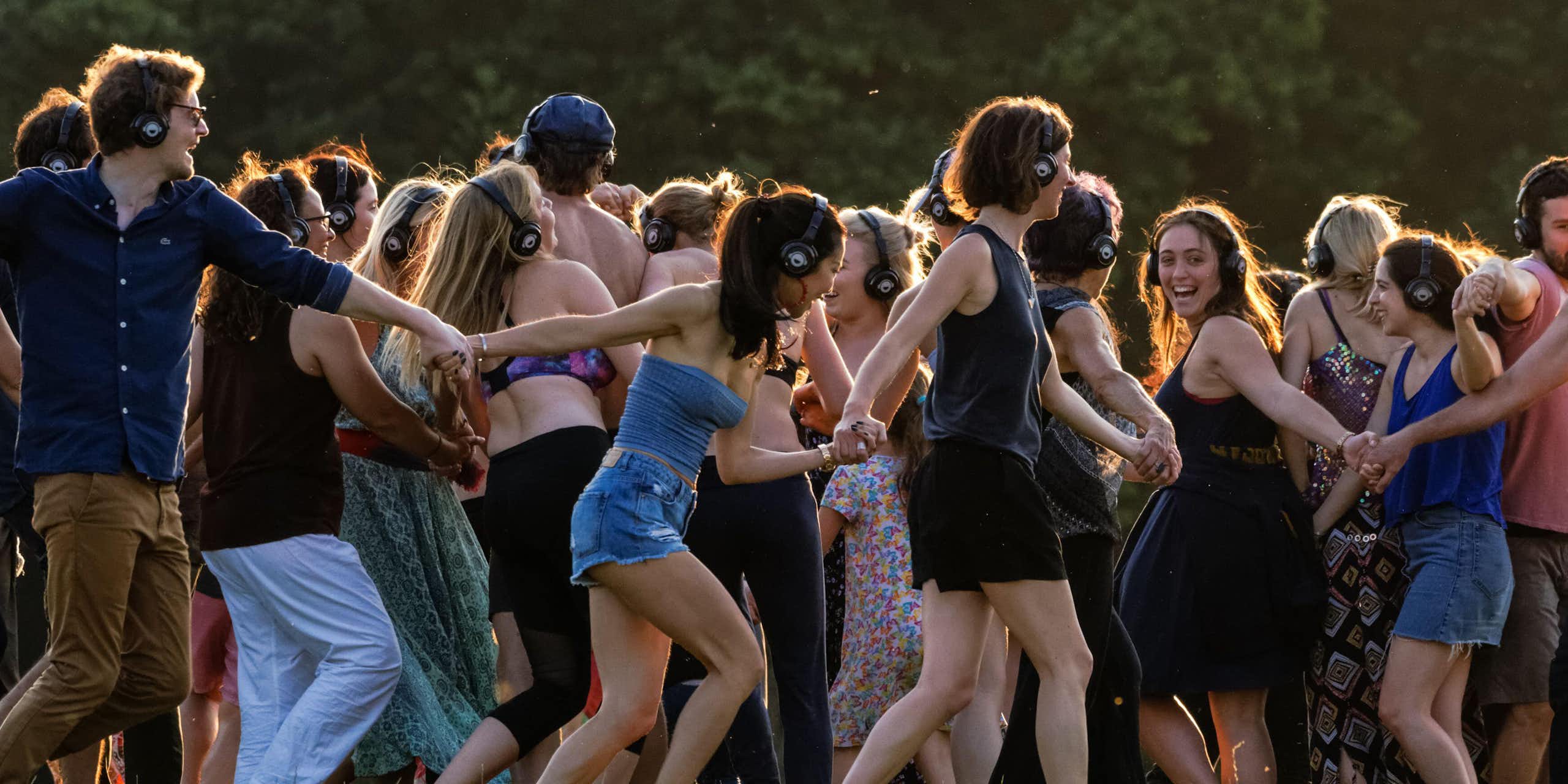 A group of young people outdoors at a festival dancing to a silent disco.