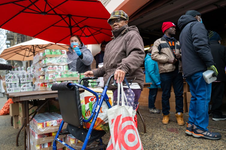 A middle-aged black woman fills her shopping cart with free food.