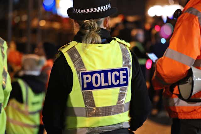View from behind of a female police officer in a high vis vest at night