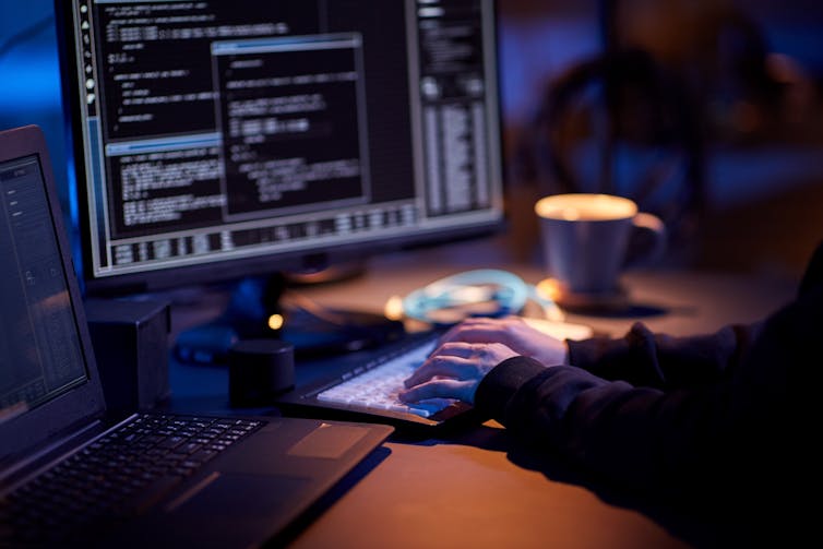 Close up of someone typing on a computer with a screen full of code