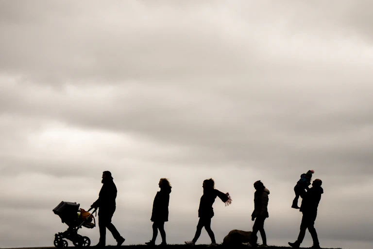 Silhouettes of a family of seven walking in a line.