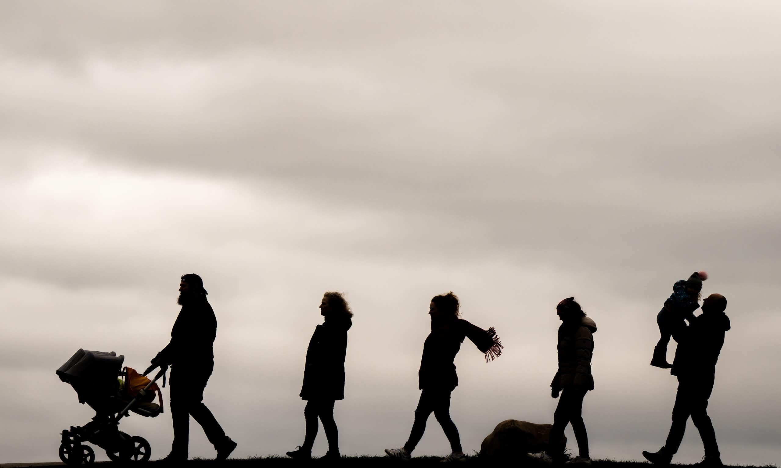 Silhouettes of a family of seven walking in a line.