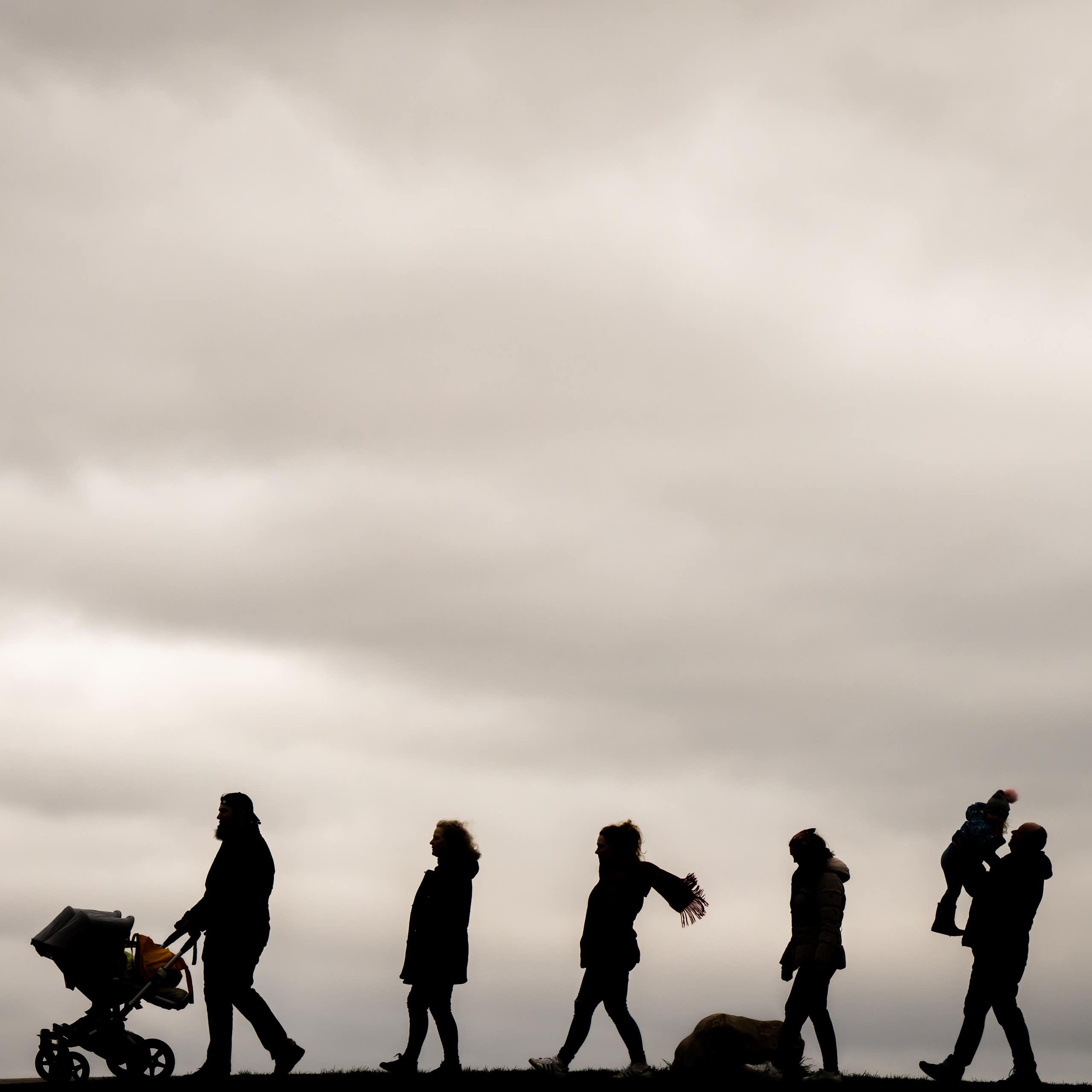 Silhouettes of a family of seven walking in a line.