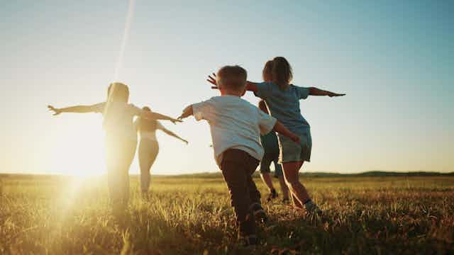 Des enfants courent vers le soleil dans un champ