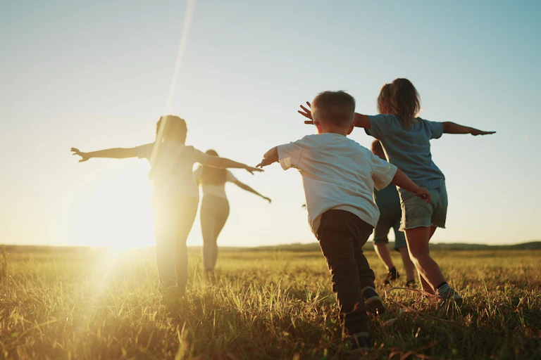Des enfants courent vers le soleil dans un champ