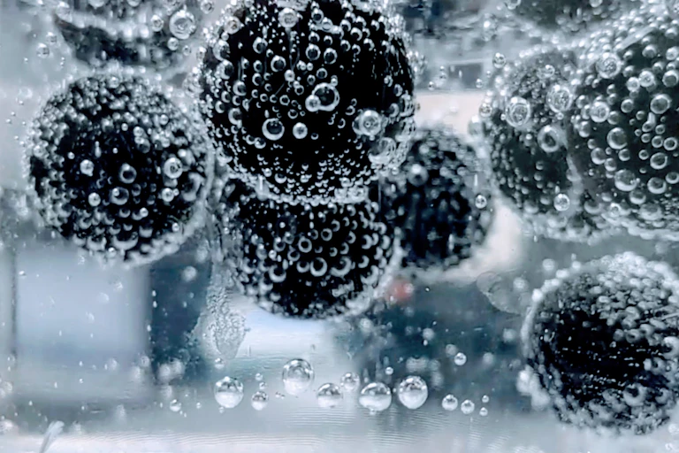 Spheres covered in bubbles are lifted upward in carbonated water.