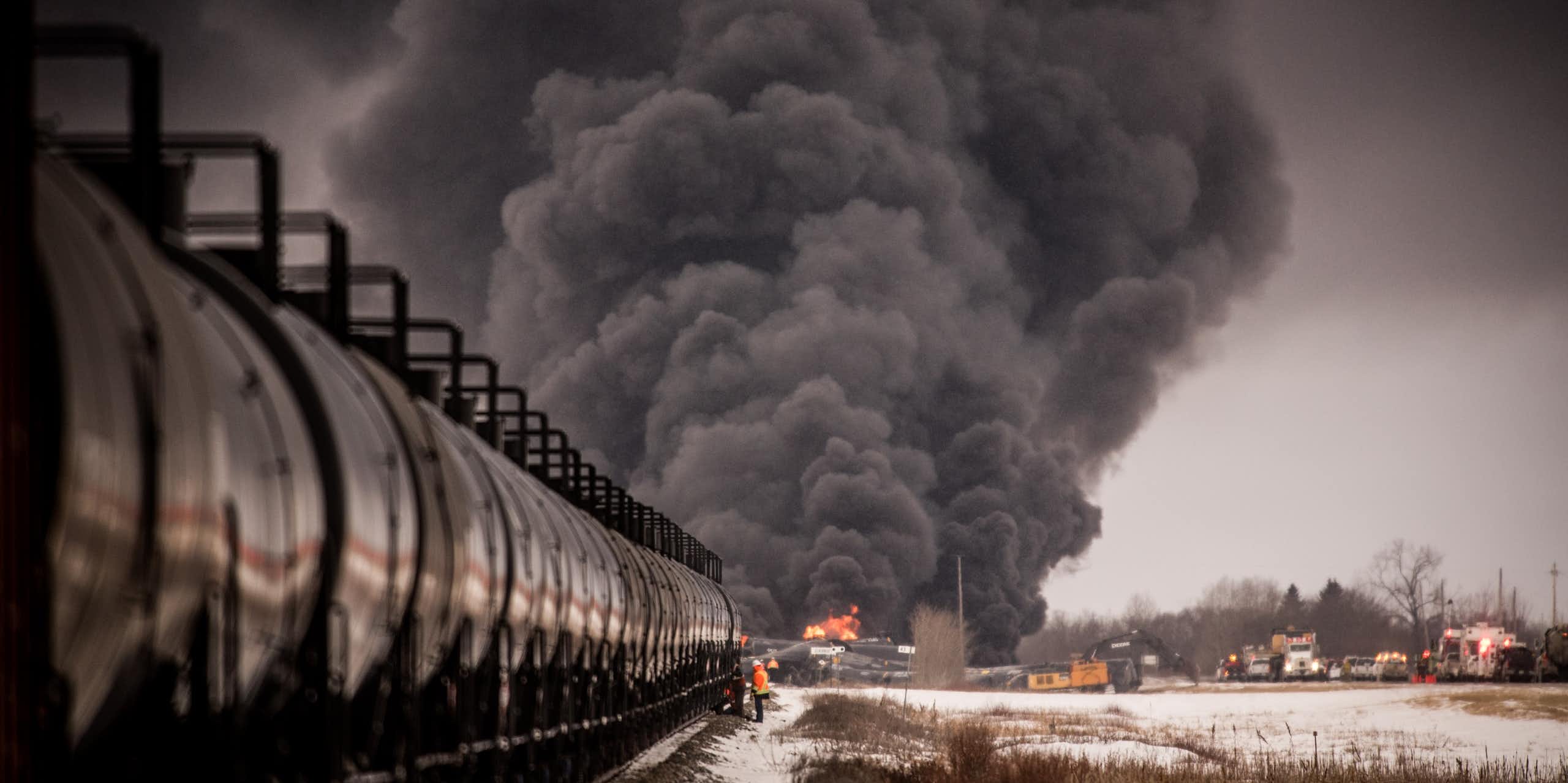 Smoke billows at the back of a black freight train.