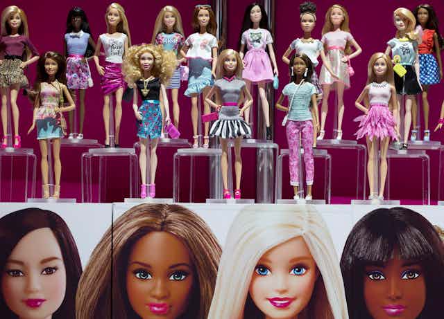 Two rows of plastic dolls with a range of skin colours stand on a display shelf
