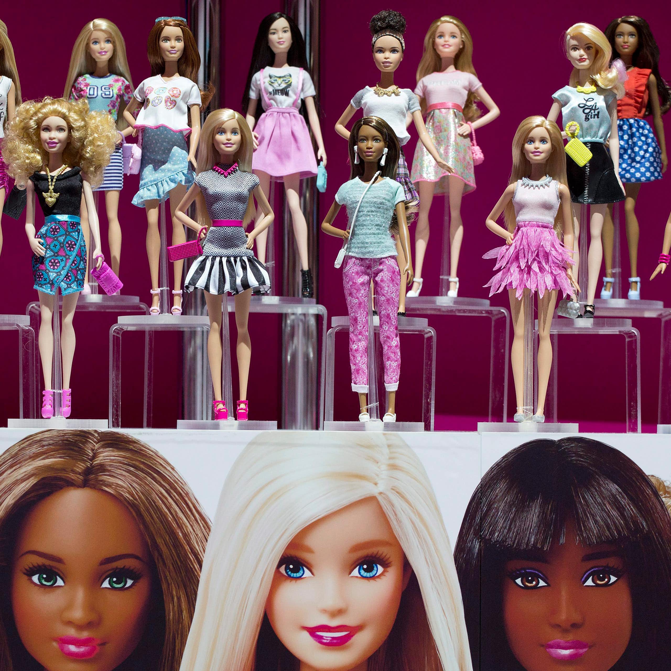 Two rows of plastic dolls with a range of skin colours stand on a display shelf