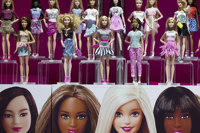 Two rows of plastic dolls with a range of skin colours stand on a display shelf