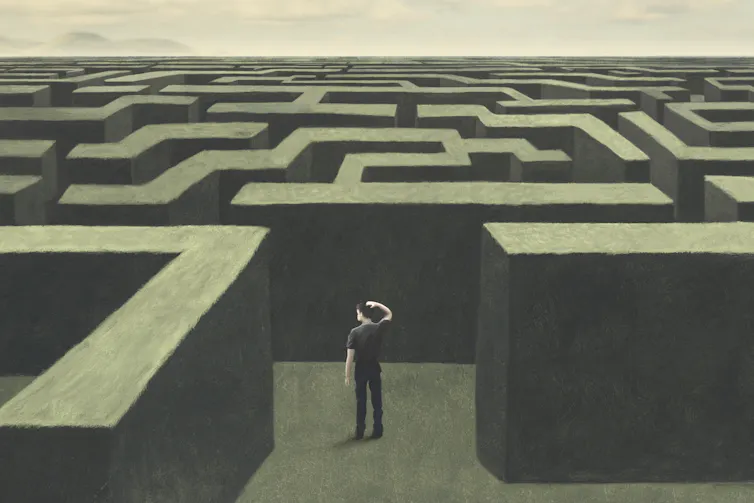 Un homme semble perdu au milieu d'un labyrinthe