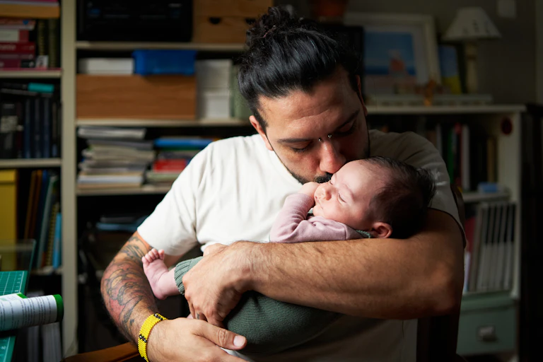 man kisses baby in his arms