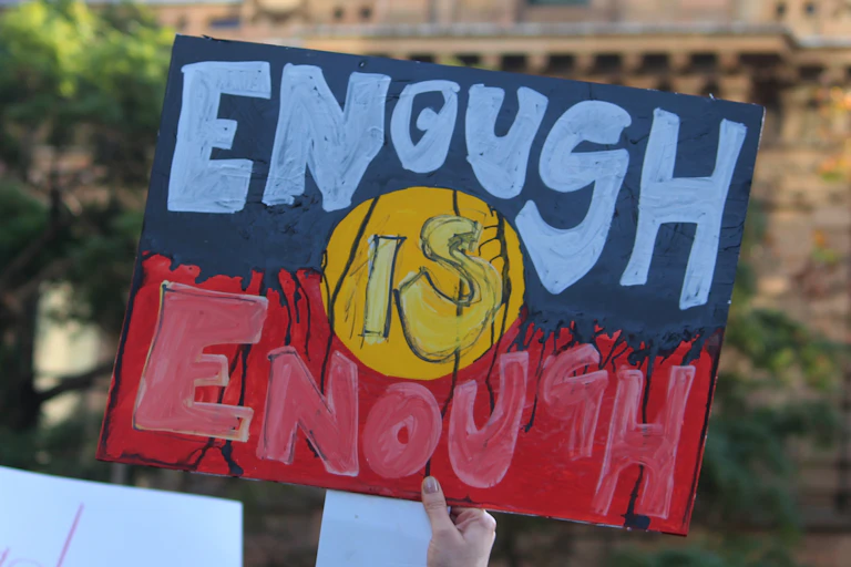 A sign in the colours and style of the Aboriginal flag saying enough is enough.