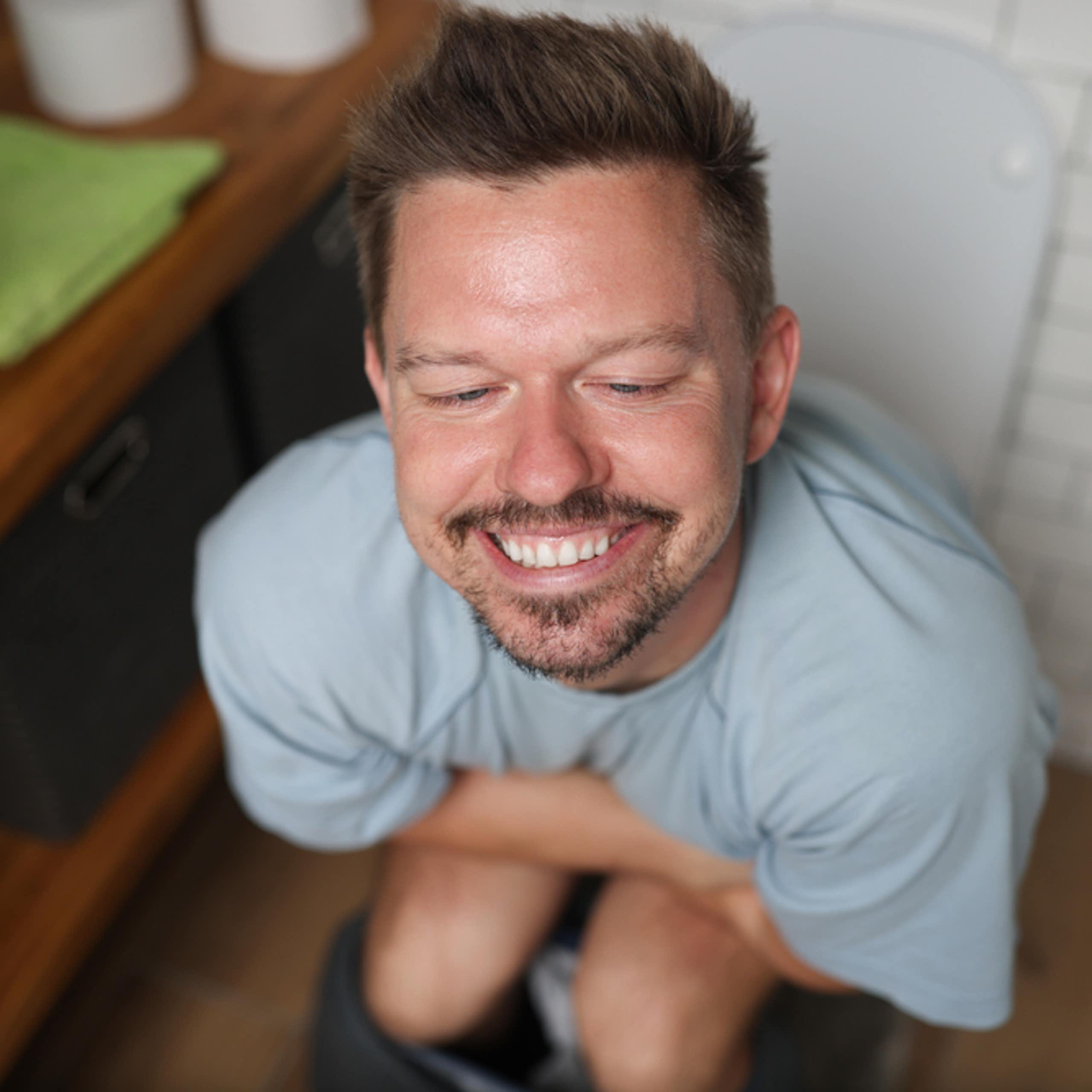 Smiling man sitting on toilet
