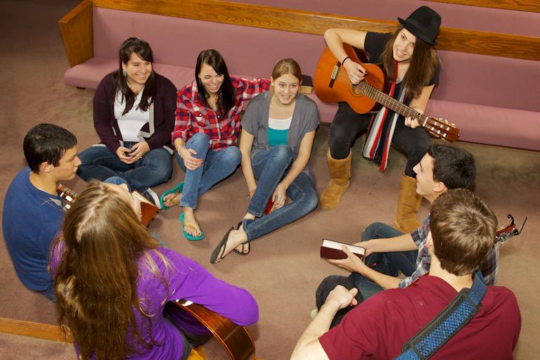 A group of young people sitting on the floor near church pews.