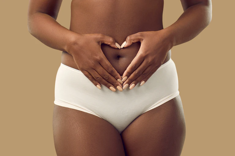 A woman holding her hands over her belly button