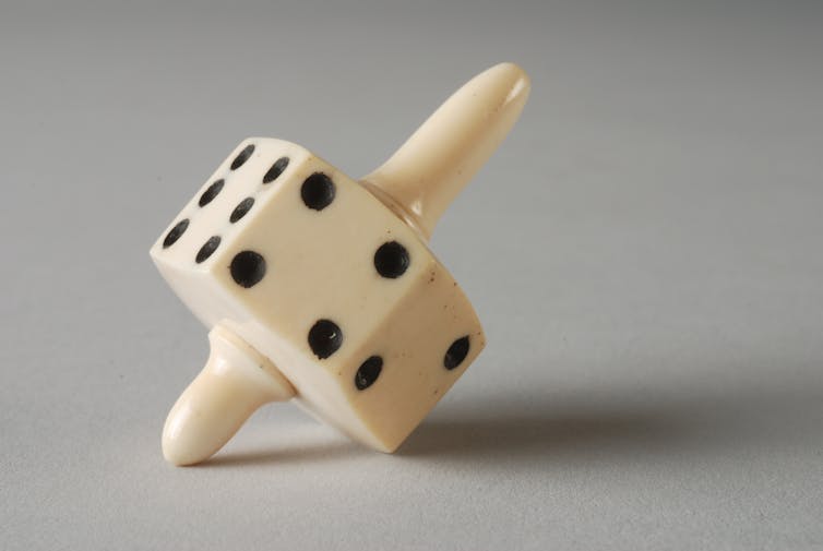 An ivory 'spinning' dice with black dots.