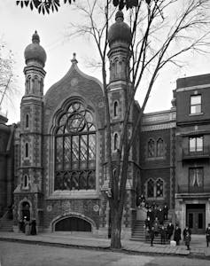 A black and white image of an old stone building with a large window featuring a Star of David.