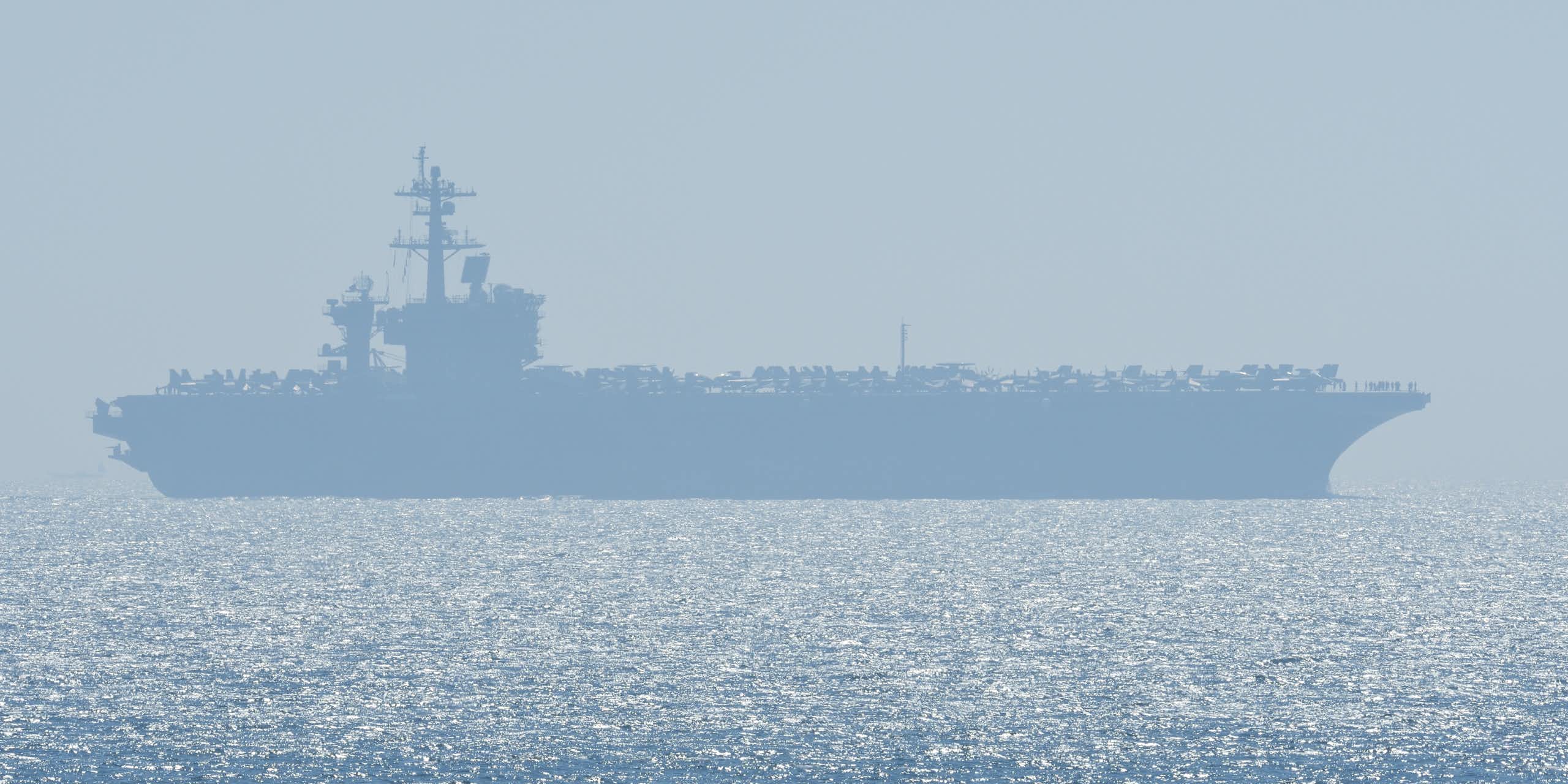 Aircraft carrier silhouetted in shimmering sea