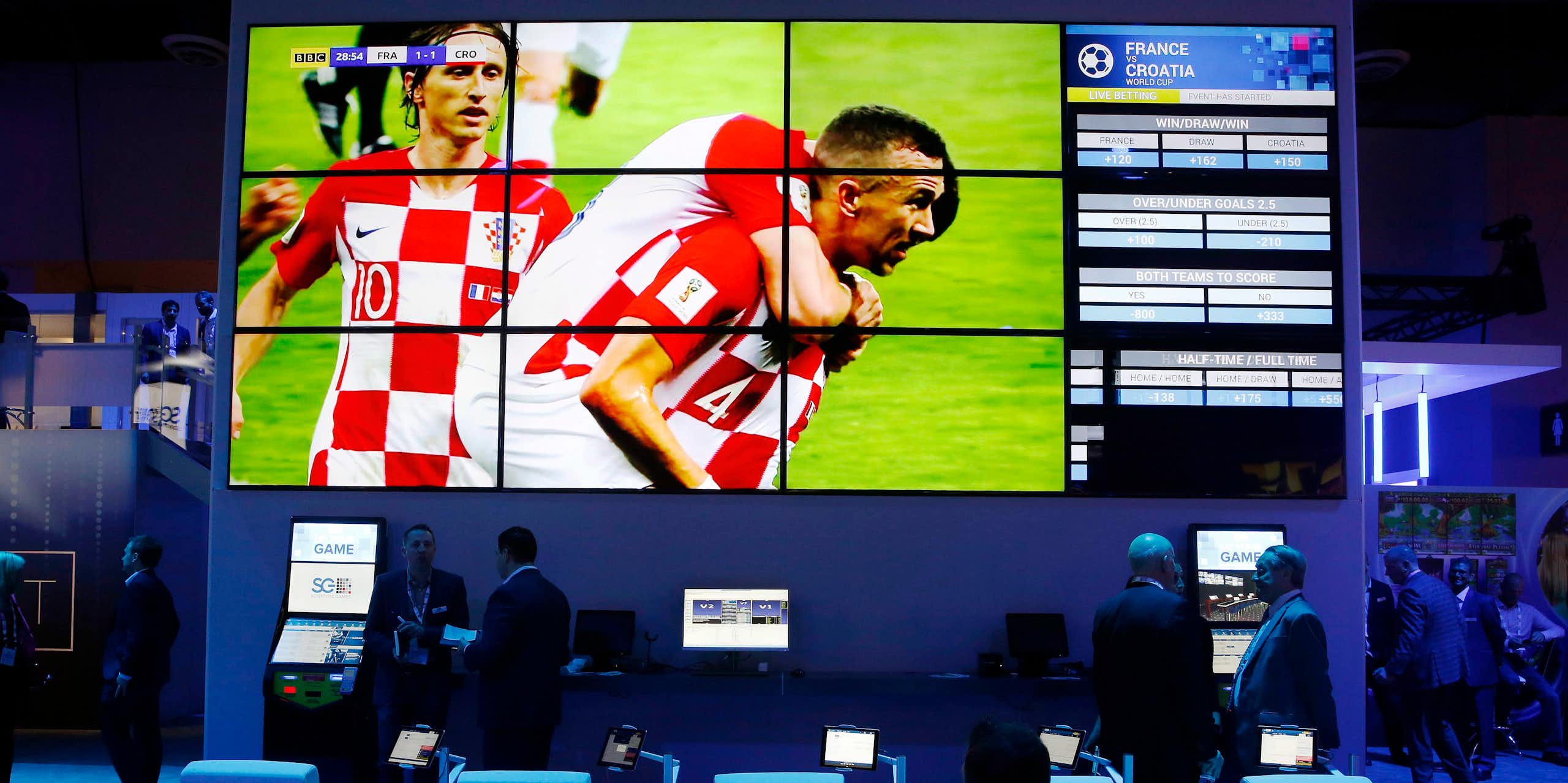 A soccer game displayed one a large screen above a row of sports betting kiosks