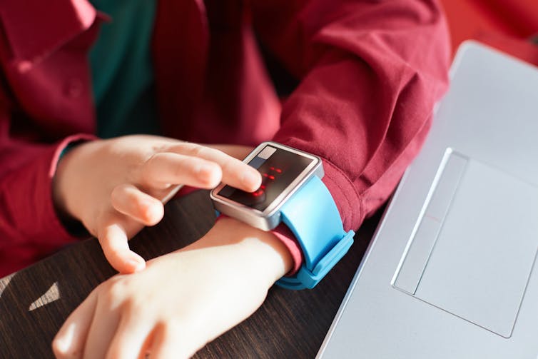 A child's hand in closeup tapping on a smartwatch screen.