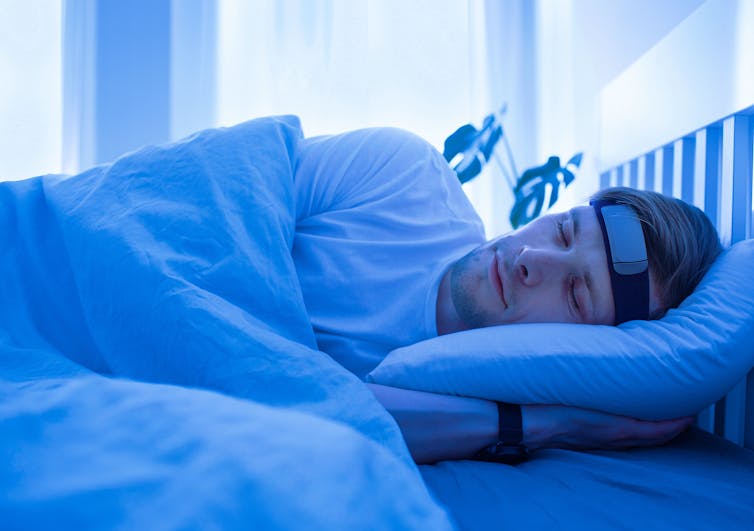 Man sleeping on bed with smart sleep headband.