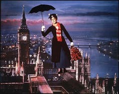 A woman flying over London with a suitcase in hand.
