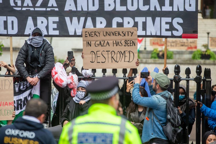 A student protest, with a prominent cardboard sign reading 'every university in gaza has been destroyed'.