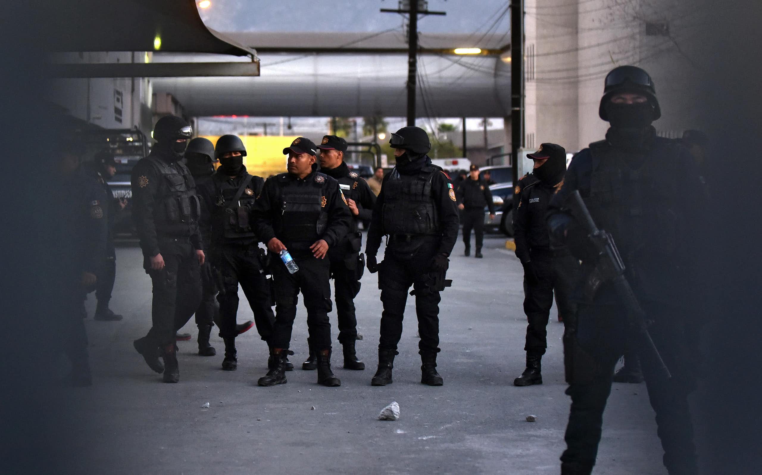 Armed Mexican policemen standing in a group in a car park.