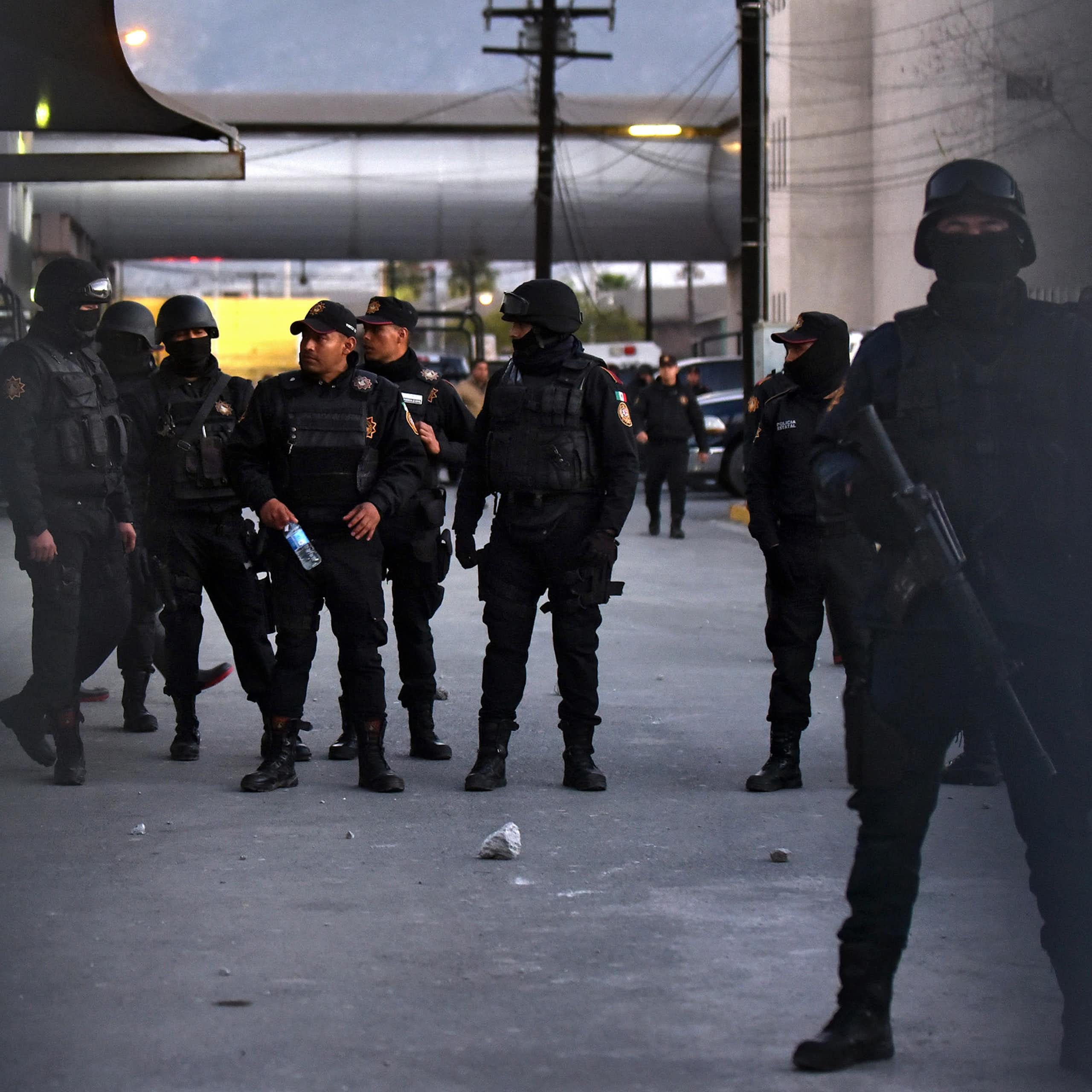 Armed Mexican policemen standing in a group in a car park.