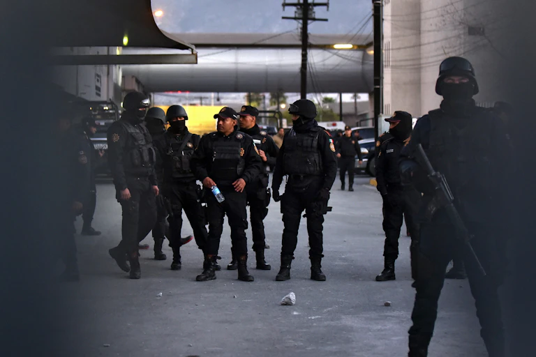 Armed Mexican policemen standing in a group in a car park.