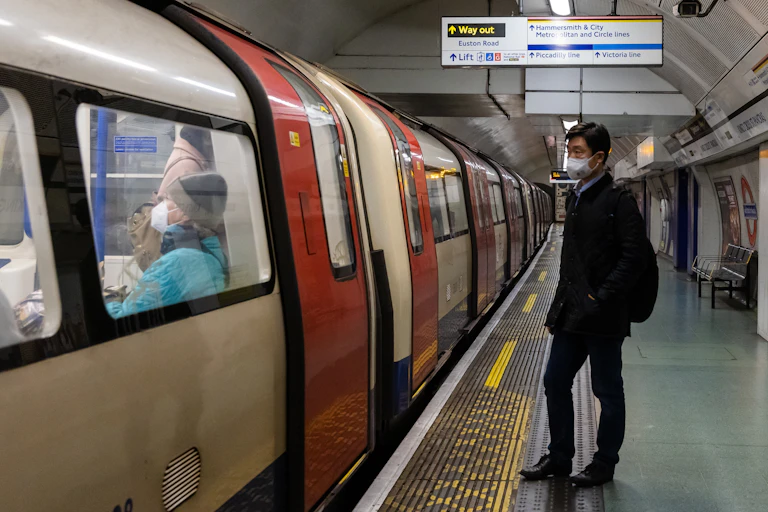 Man wearing a mask, standing on London Underground platform
