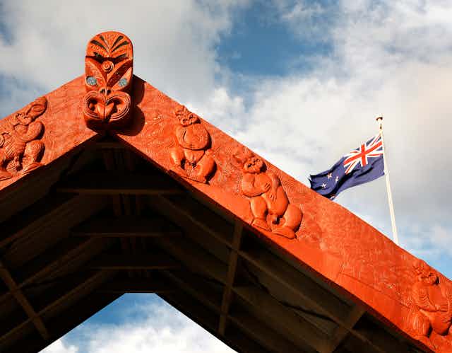 Maori carved archway with NZ flag in background