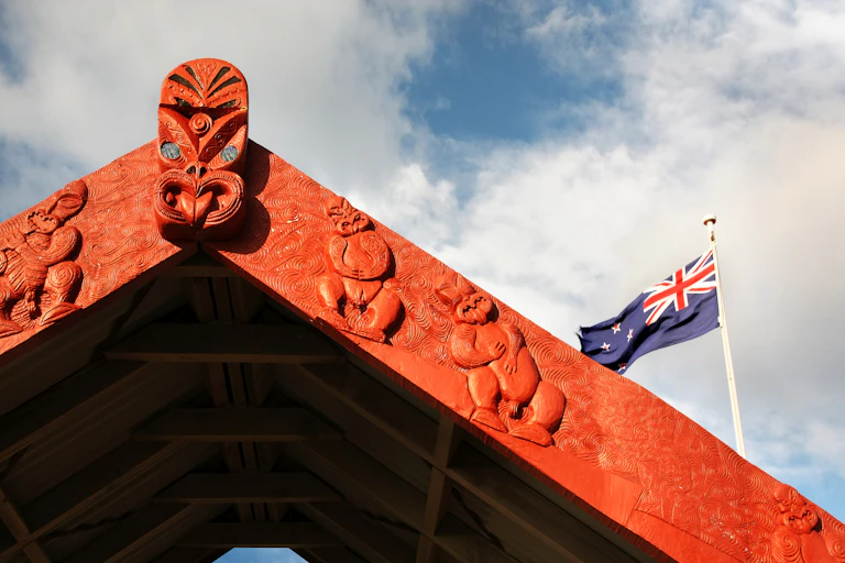 Maori carved archway with NZ flag in background