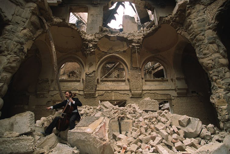 El violonchelista local Vedran Smailović toca entre las ruinas de la Biblioteca Nacional de Sarajevo durante la guerra en 1992.