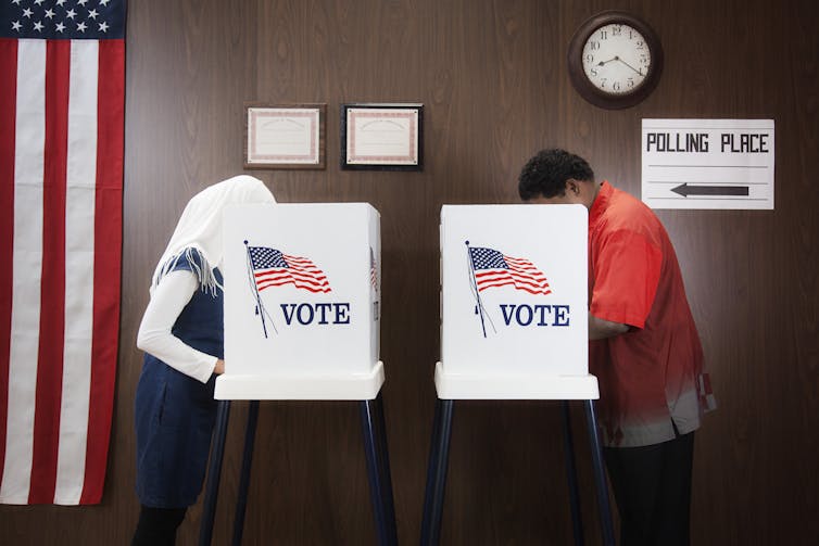 Two people, a man and a woman, standing in voting booths.