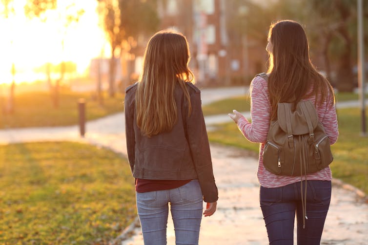 Two young women walking in park