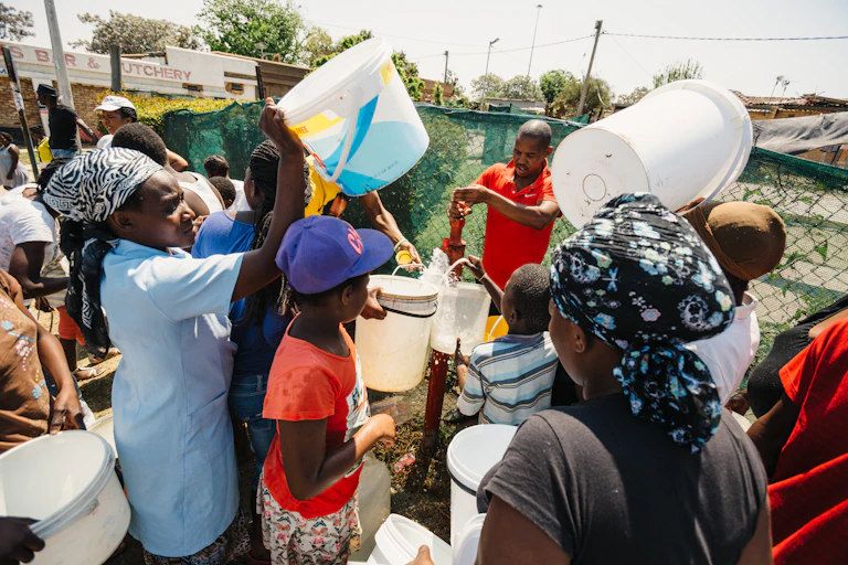 Women and children collect water from a water hydrant.