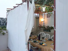A tent-like structure with a white sheet wall and a table set for a meal inside.