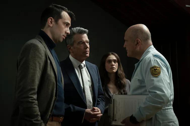 Three people seen in an intense exchange of staring while one looks on.