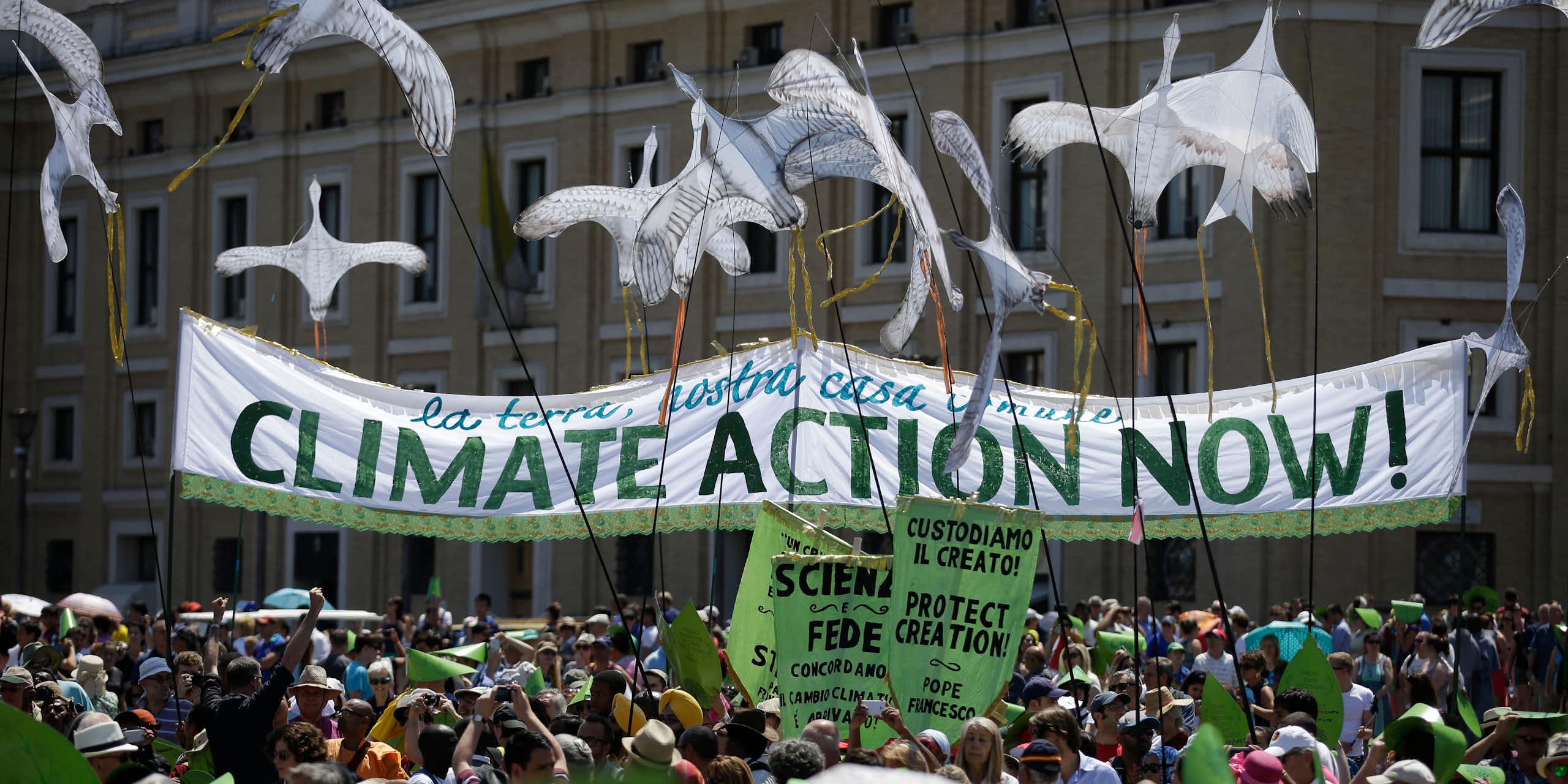 People outside an ornate building hold a sign that says 'Climate action now!'