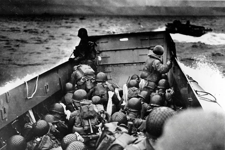 A black-and-white image shows helmeted soldiers jammed into a small watercraft heading through rough seas.