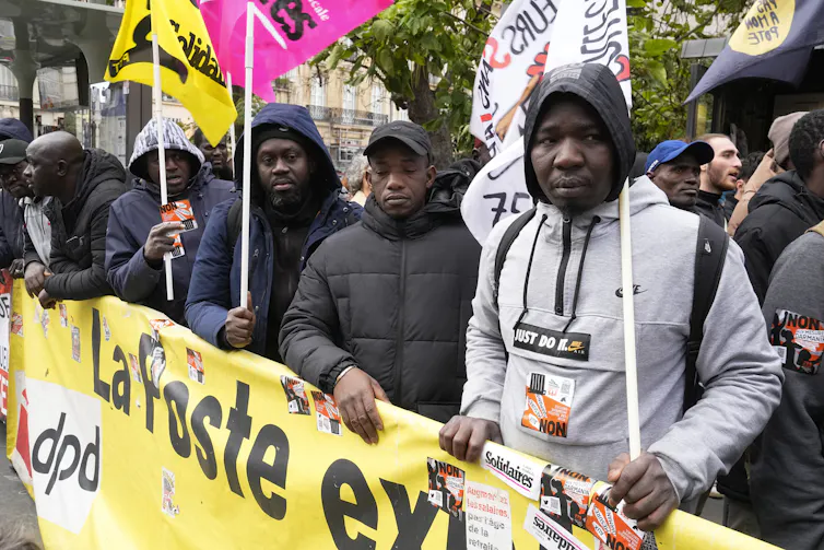 Des hommes tiennent un bandeau et des drapeaux