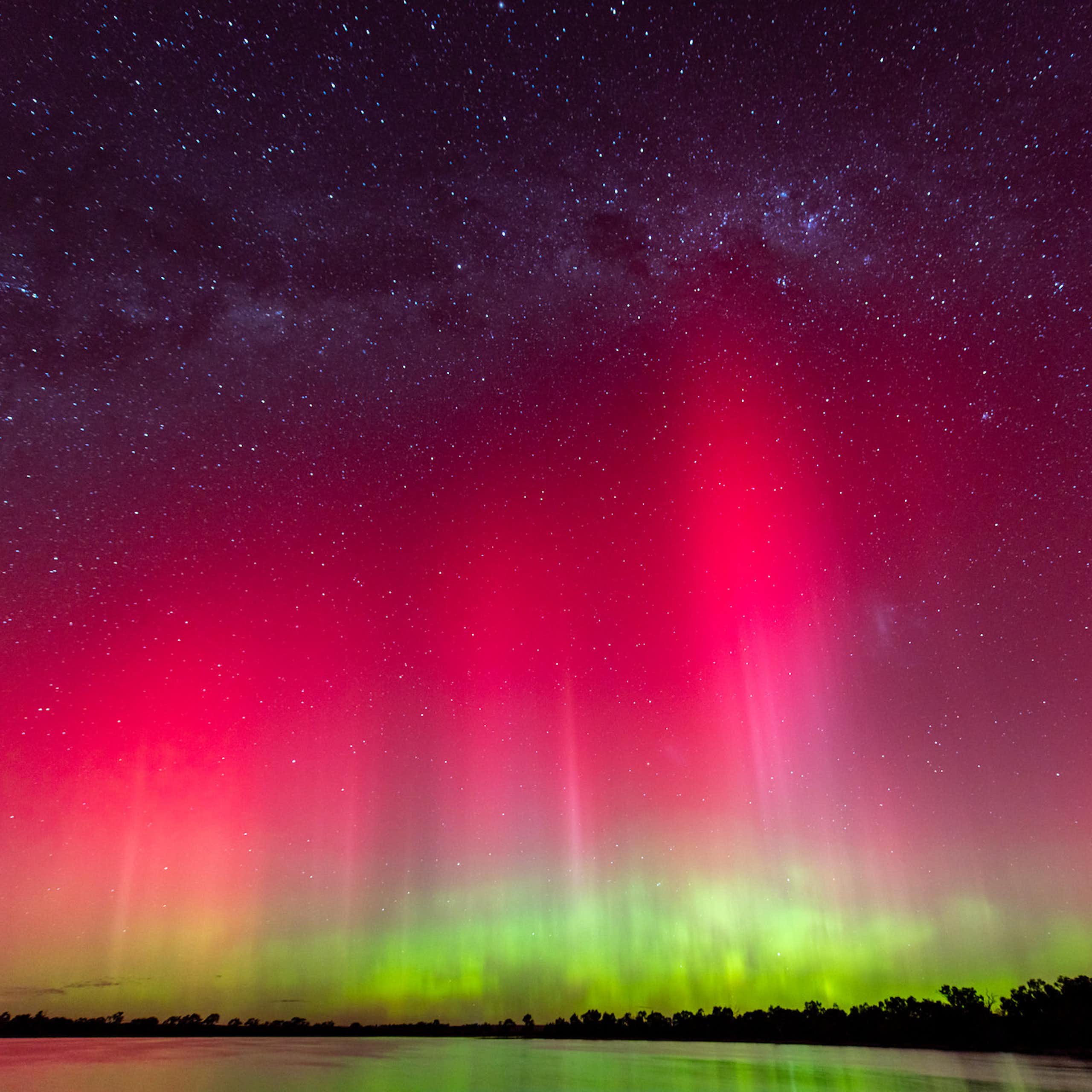 A bright pink and red sky with green lights underneath.