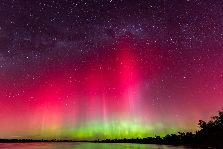 A bright pink and red sky with green lights underneath.