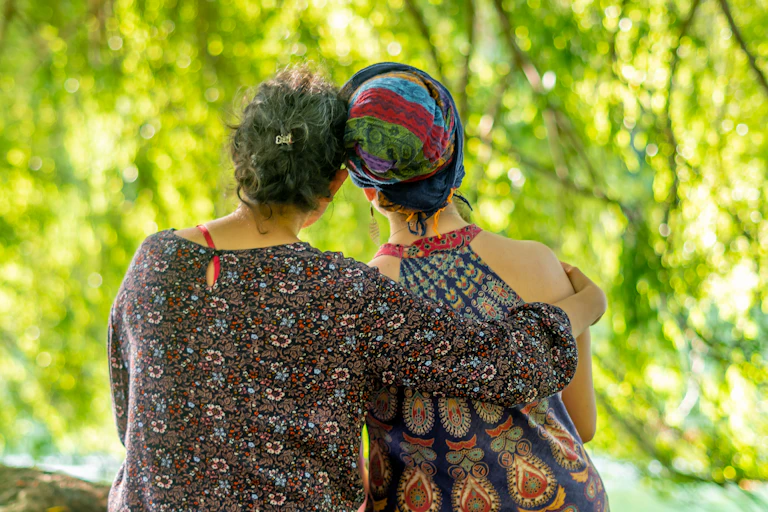 A woman sitting next to and holding another wearing a headscarf