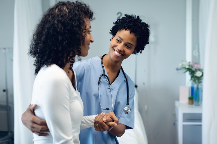 A smiling nurse supports a patient.
